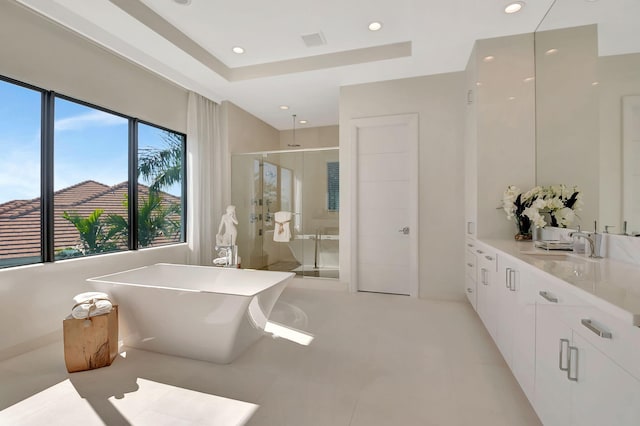 bathroom featuring tile patterned flooring, shower with separate bathtub, a tray ceiling, and vanity