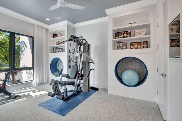 workout area featuring ornamental molding, built in shelves, ceiling fan, and carpet flooring