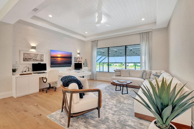 living room featuring built in desk, wood ceiling, light wood-type flooring, and a tray ceiling