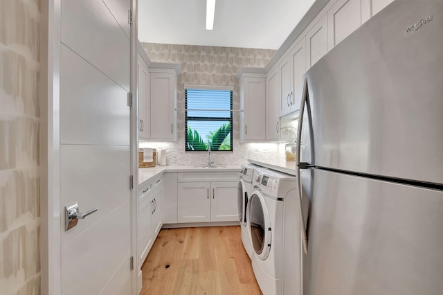 laundry room with washer and dryer, light wood-type flooring, and sink