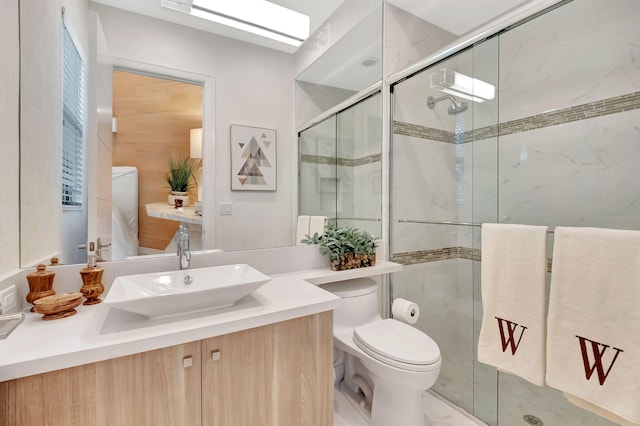 bathroom with toilet, a shower with door, a skylight, and vanity