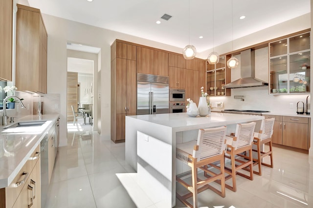 kitchen with a breakfast bar, stainless steel appliances, a center island, and wall chimney exhaust hood