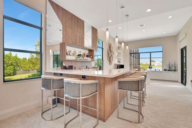 kitchen featuring decorative light fixtures, a kitchen breakfast bar, plenty of natural light, and kitchen peninsula