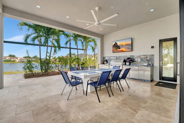 view of patio featuring an outdoor kitchen, ceiling fan, a grill, and a water view