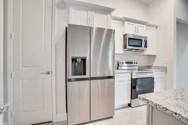 kitchen featuring white cabinets, light stone counters, and appliances with stainless steel finishes