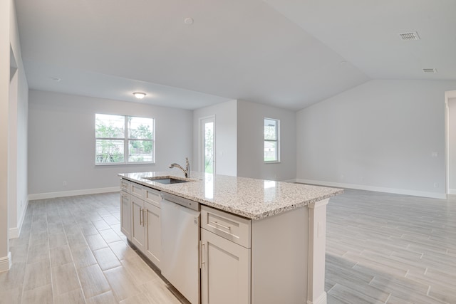 kitchen featuring a center island with sink, light stone countertops, white dishwasher, and plenty of natural light