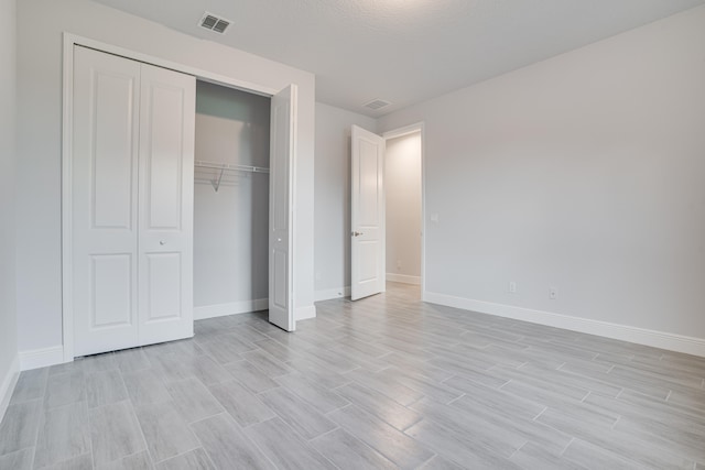 unfurnished bedroom with a closet, a textured ceiling, and light hardwood / wood-style floors