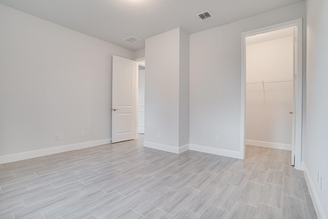 empty room with light wood-type flooring and a textured ceiling