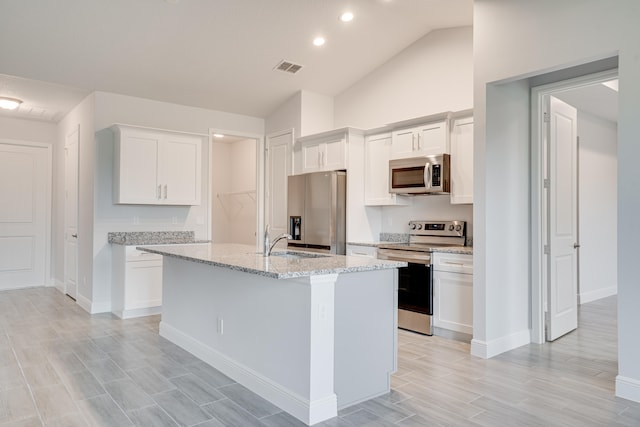 kitchen featuring a center island with sink, sink, white cabinetry, appliances with stainless steel finishes, and lofted ceiling