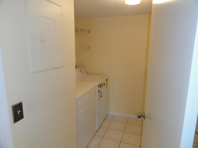 laundry room featuring a textured ceiling, electric panel, washer and clothes dryer, and light tile patterned flooring