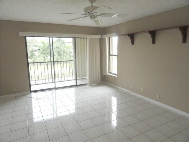 tiled spare room with a textured ceiling, ceiling fan, and a healthy amount of sunlight