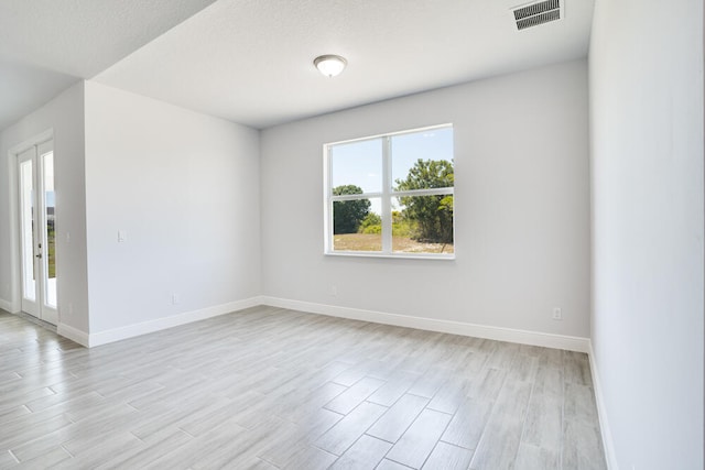 unfurnished room with a textured ceiling and light hardwood / wood-style flooring