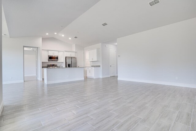 unfurnished living room with light wood-type flooring and lofted ceiling