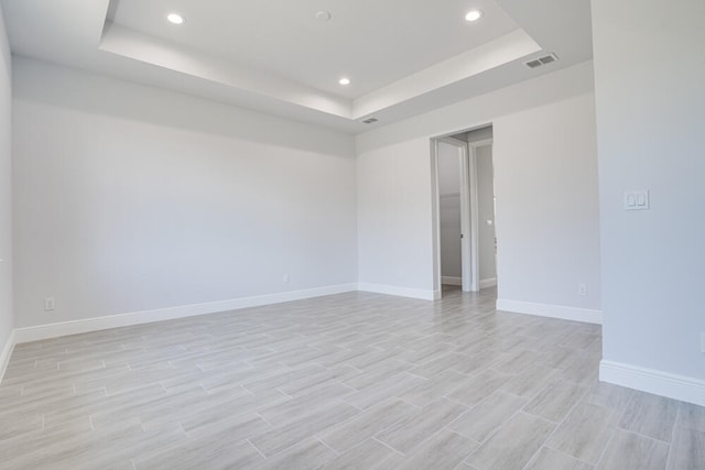 unfurnished room with light hardwood / wood-style flooring and a raised ceiling