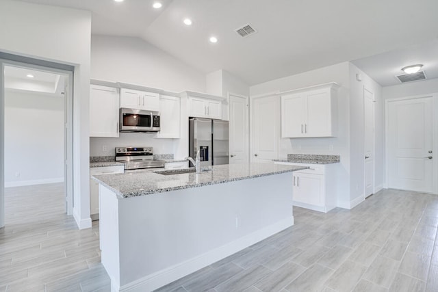 kitchen featuring white cabinetry, stainless steel appliances, and lofted ceiling