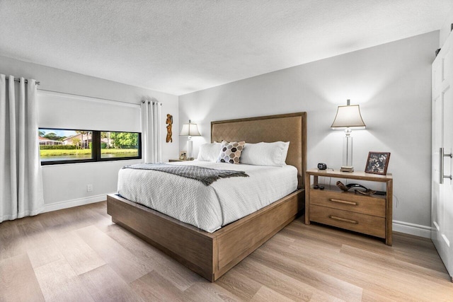 bedroom featuring a textured ceiling and light hardwood / wood-style floors