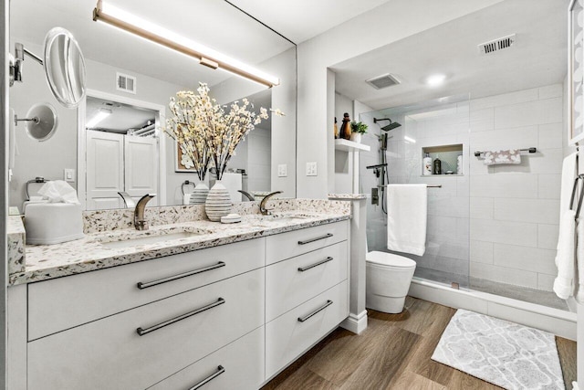 bathroom featuring tiled shower, hardwood / wood-style floors, vanity, and toilet