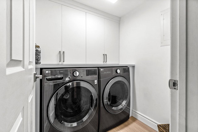 laundry area with washing machine and dryer, cabinets, and light wood-type flooring