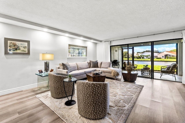 living room with a textured ceiling, a water view, and light hardwood / wood-style flooring