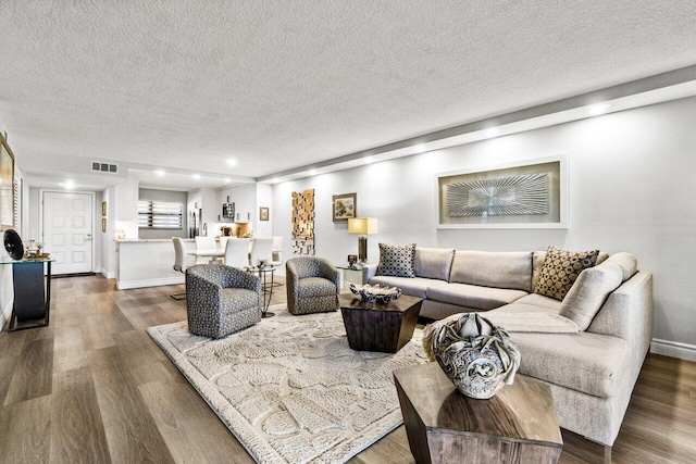 living room with a textured ceiling and dark hardwood / wood-style floors