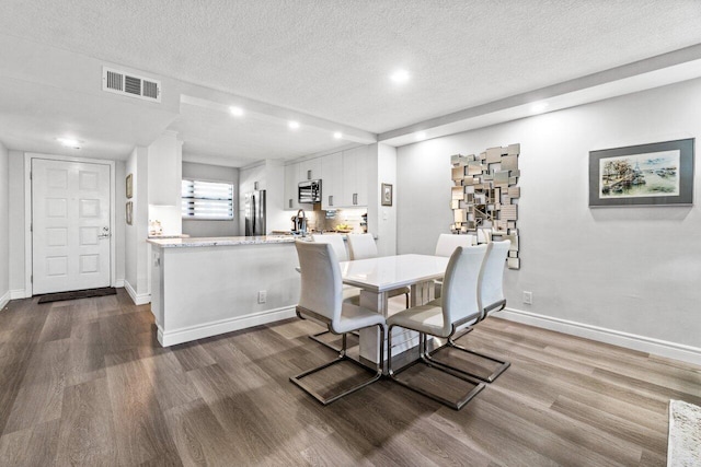 dining space with a textured ceiling and dark hardwood / wood-style floors