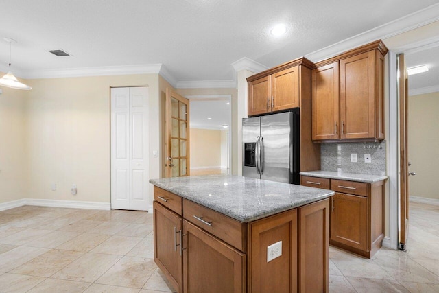 kitchen featuring stainless steel fridge, tasteful backsplash, light stone counters, ornamental molding, and a center island