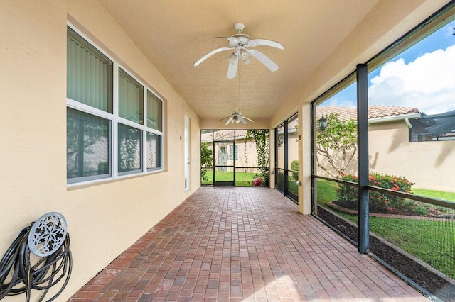 unfurnished sunroom with ceiling fan and plenty of natural light