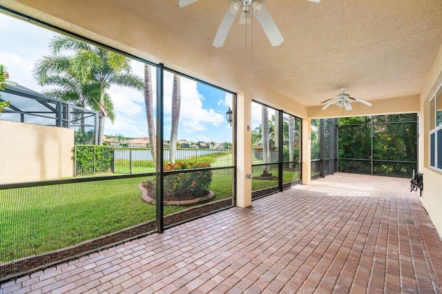 unfurnished sunroom featuring a water view and ceiling fan