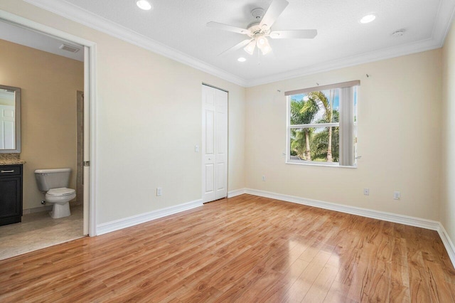 unfurnished bedroom with ensuite bath, ceiling fan, crown molding, light hardwood / wood-style floors, and a closet