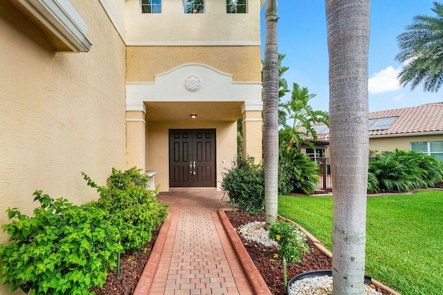 view of exterior entry featuring a lawn