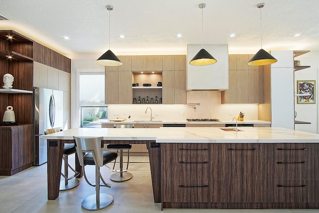 kitchen with a textured ceiling, stainless steel appliances, sink, and decorative light fixtures