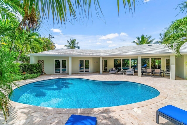 outdoor pool featuring outdoor lounge area, a patio, and french doors