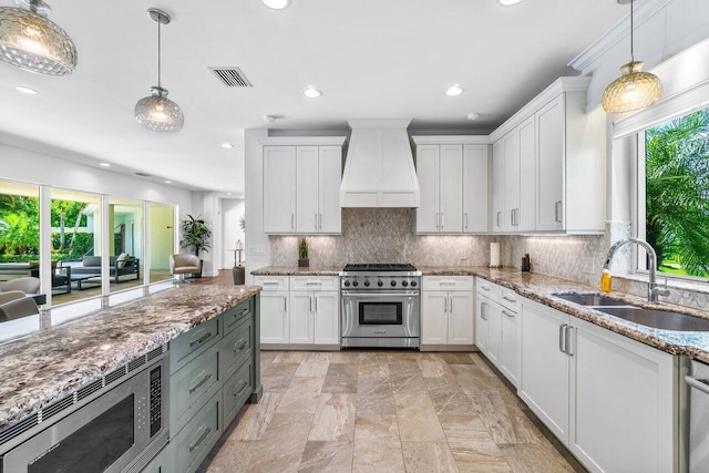 kitchen featuring white cabinetry, sink, hanging light fixtures, premium range hood, and appliances with stainless steel finishes