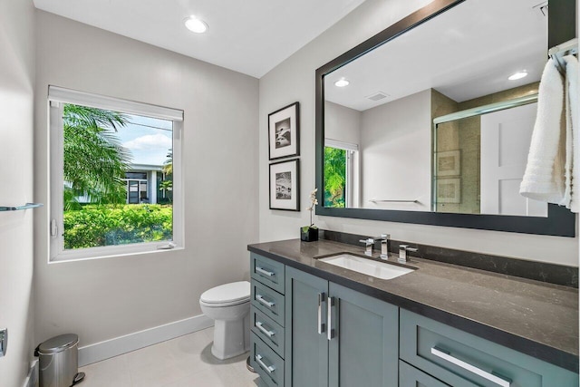 bathroom with tile patterned floors, vanity, a shower with shower door, and a wealth of natural light