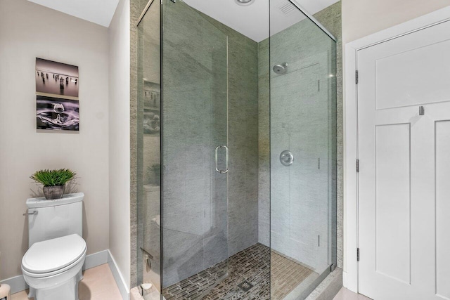 bathroom featuring a shower with door and toilet