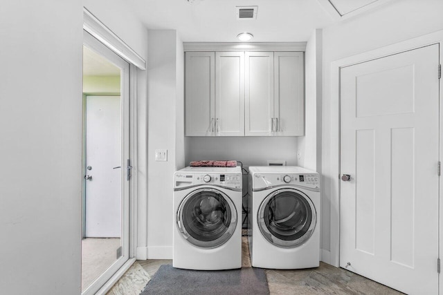 clothes washing area featuring cabinets and washer and clothes dryer