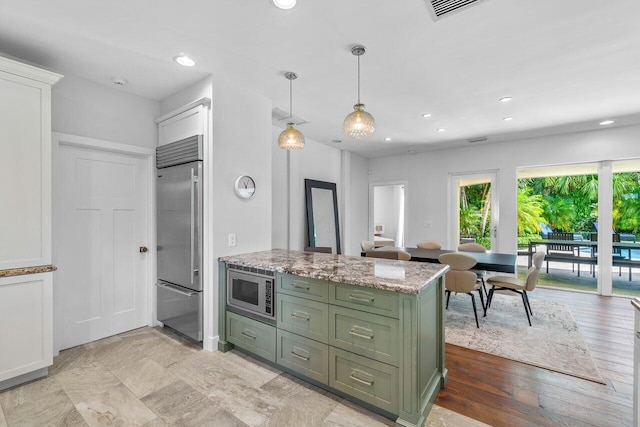 kitchen with light stone counters, built in appliances, light hardwood / wood-style flooring, green cabinetry, and white cabinets