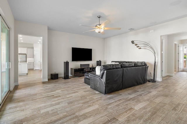 living room with ceiling fan, a wealth of natural light, and light hardwood / wood-style flooring