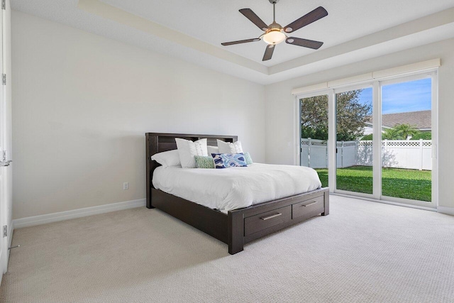 bedroom with ceiling fan, a raised ceiling, light carpet, and access to outside