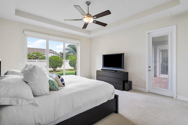 carpeted bedroom with access to outside, a raised ceiling, and ceiling fan