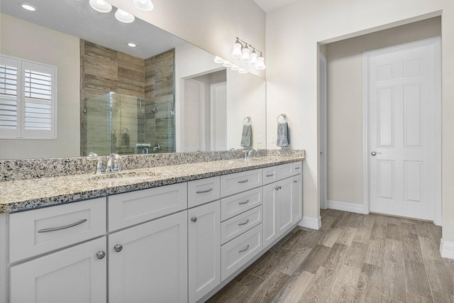 bathroom with hardwood / wood-style flooring, vanity, and a shower with shower door