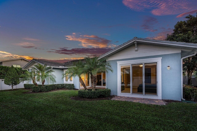 back house at dusk featuring a yard