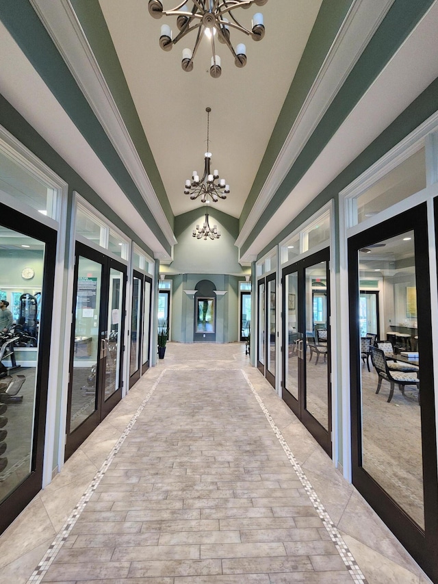 hall featuring french doors, lofted ceiling, a notable chandelier, and a healthy amount of sunlight