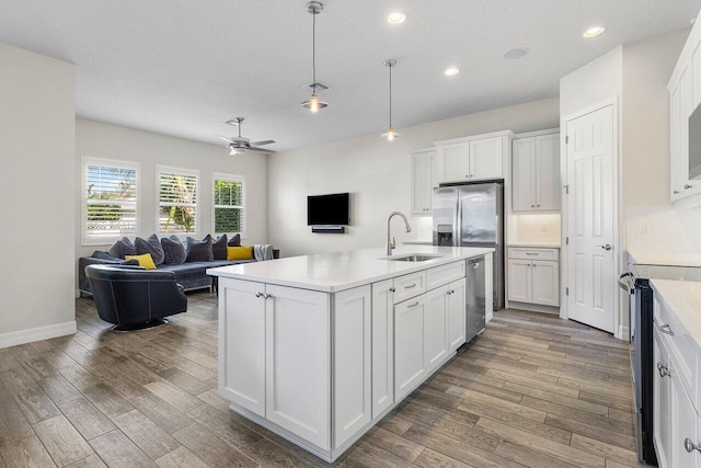 kitchen with white cabinets, sink, appliances with stainless steel finishes, decorative light fixtures, and dark hardwood / wood-style flooring