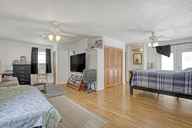 workout room featuring a textured ceiling, light wood-type flooring, a wealth of natural light, and ceiling fan