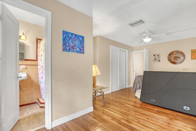 bedroom featuring multiple windows, a textured ceiling, light hardwood / wood-style flooring, and ceiling fan