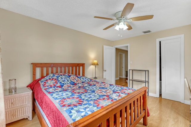 bedroom with a textured ceiling, light hardwood / wood-style floors, and ceiling fan