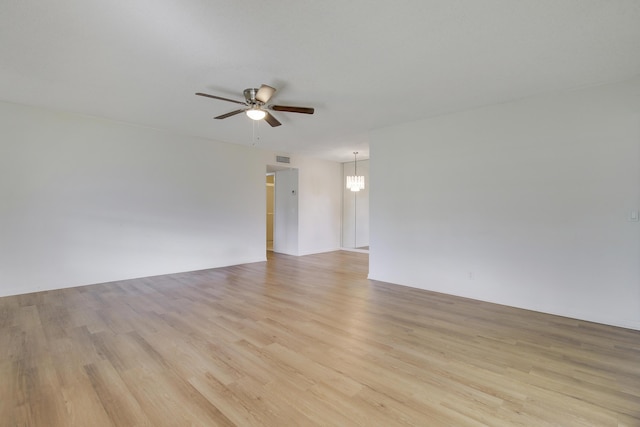 spare room featuring ceiling fan with notable chandelier and light hardwood / wood-style flooring