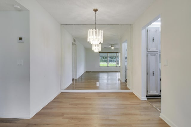 corridor featuring light hardwood / wood-style flooring, a chandelier, and a textured ceiling