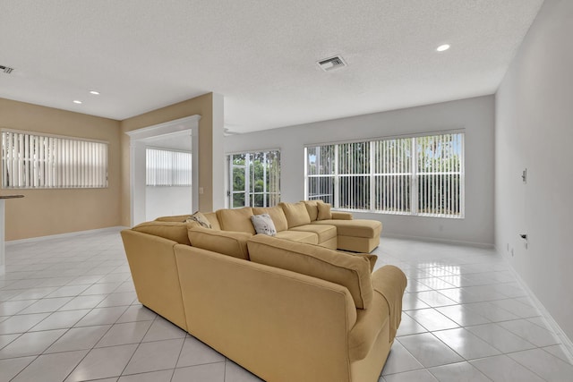 living room featuring a wealth of natural light, a textured ceiling, and light tile patterned flooring